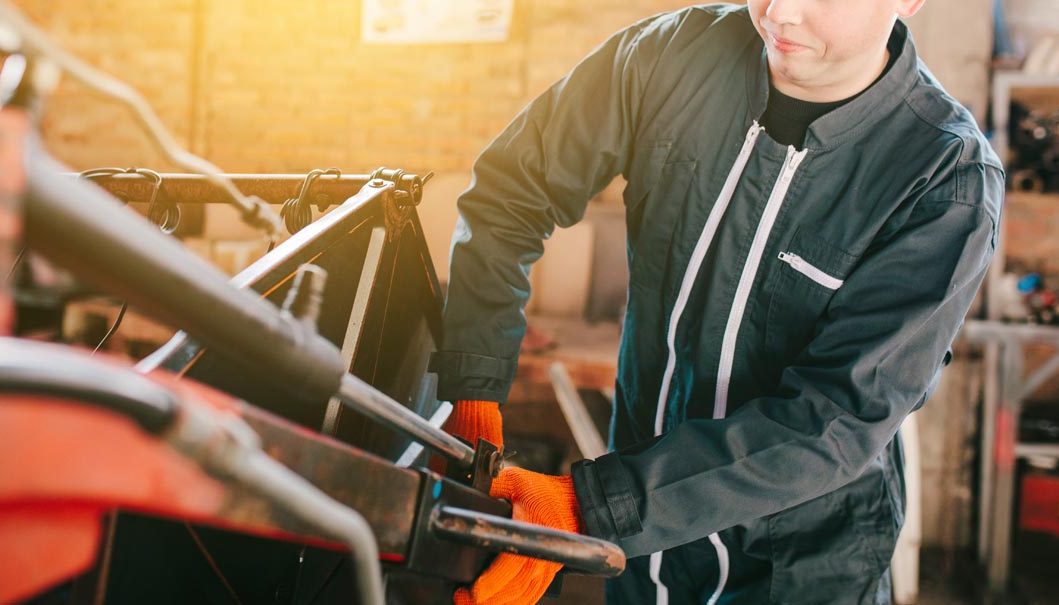 A mechanic is repairing a tractor used in agriculture.